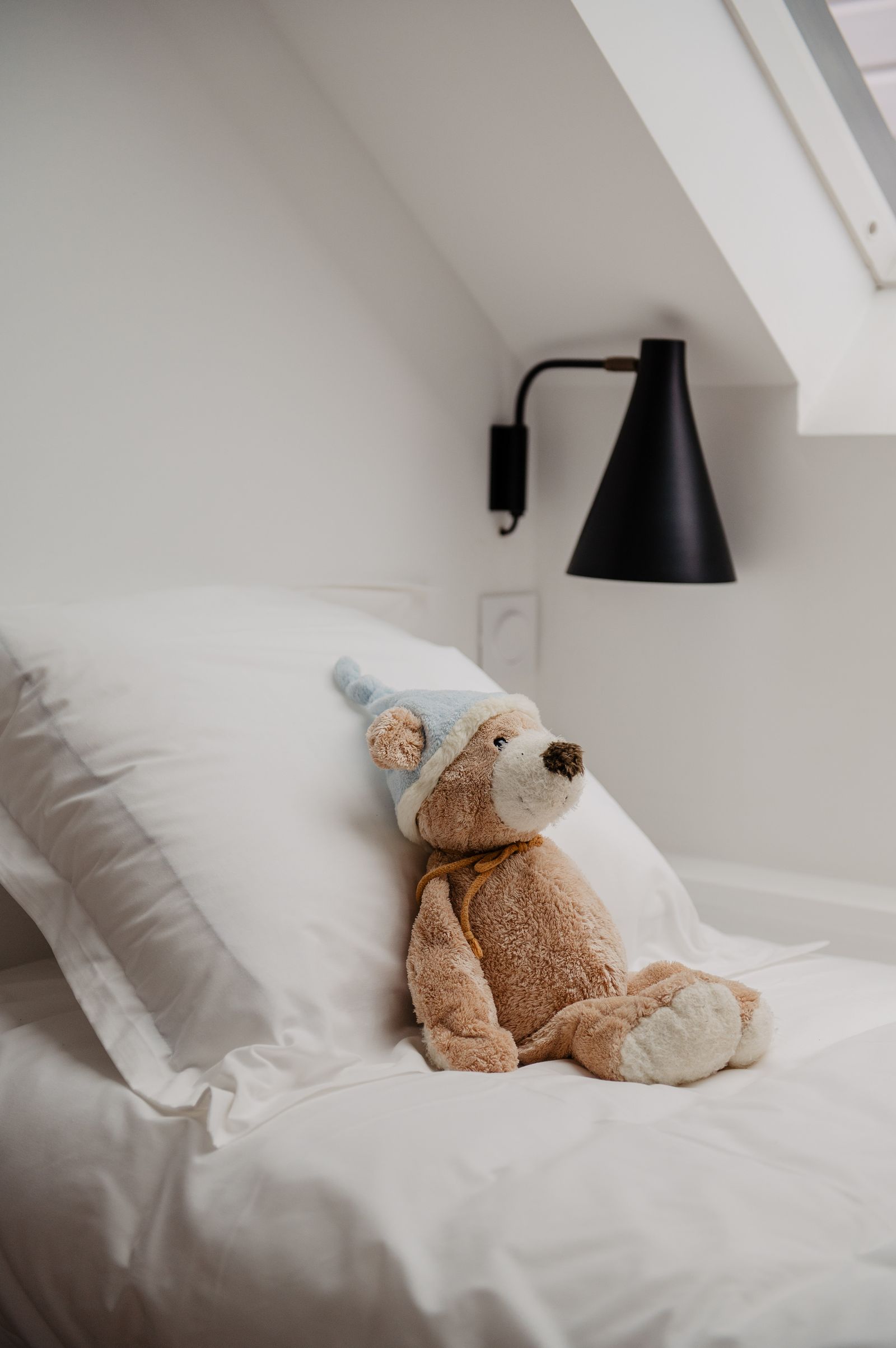 Ein Teddybär und gestreifte Handtücher auf einem Bett im Kinderzimmer